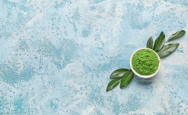 Renkli arkaplanda bir kase toz kibrit çayı ve taze yapraklı kompozisyon