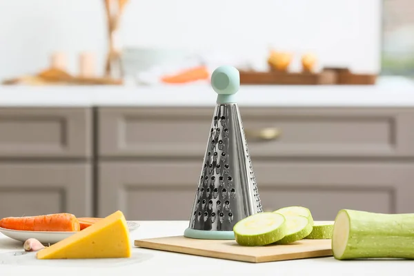 Metal grater and zucchini on kitchen table