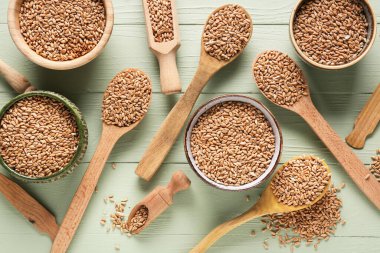 Tahta arka planda buğday taneleri olan kâseler ve kaşıklar.