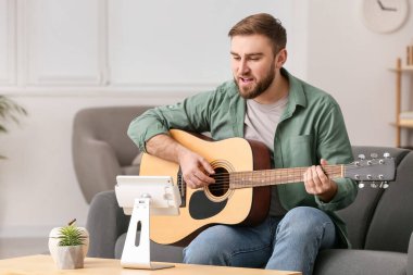 Genç adam evde online müzik dersleri alıyor.