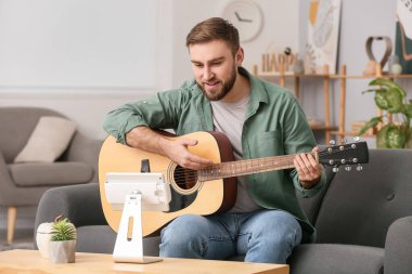 Genç adam evde online müzik dersleri alıyor.