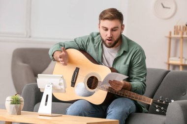 Genç adam evde online müzik dersleri alıyor.