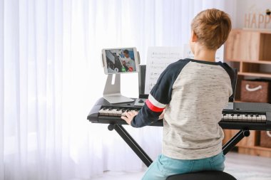 Küçük çocuk evde arkadaşıyla internet üzerinden müzik eğitimi görüyor.