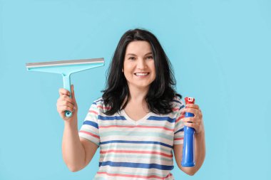 Deterjan ve arka planda cam sileceği olan olgun bir kadın.