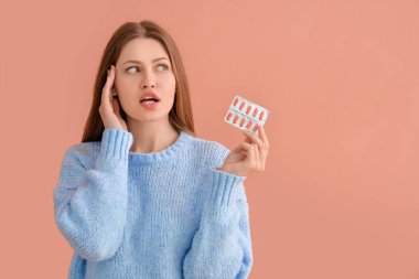 Renkli hapları olan düşünceli bir genç kadın.