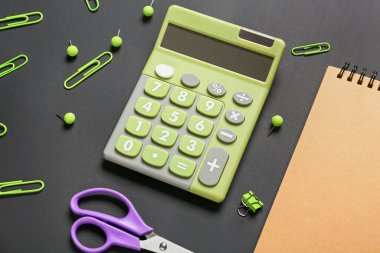 Koyu arkaplan üzerinde modern hesap makinesi ve kırtasiye