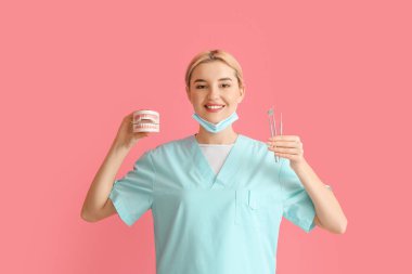 Renk arkaplan üzerinde plastik çene modeline sahip kadın dişçi