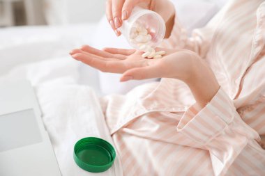 Hasta genç kadın evde hap alıyor, yakın plan.