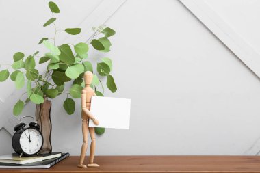 Masasında boş poster ve dekor olan ahşap manken.
