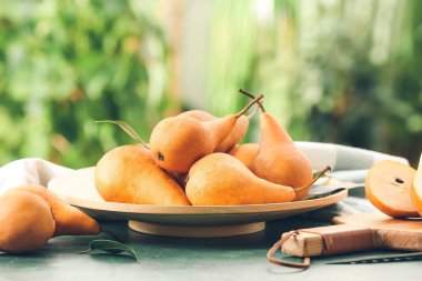 Bulanık arka planda taze olgun armutlarla kaplı bir tabak.