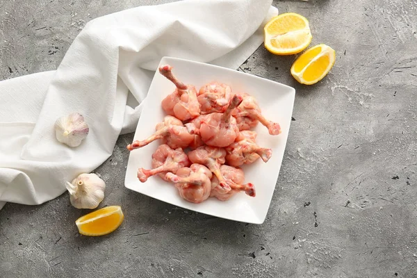 Plate with raw chicken lollipops on grey background