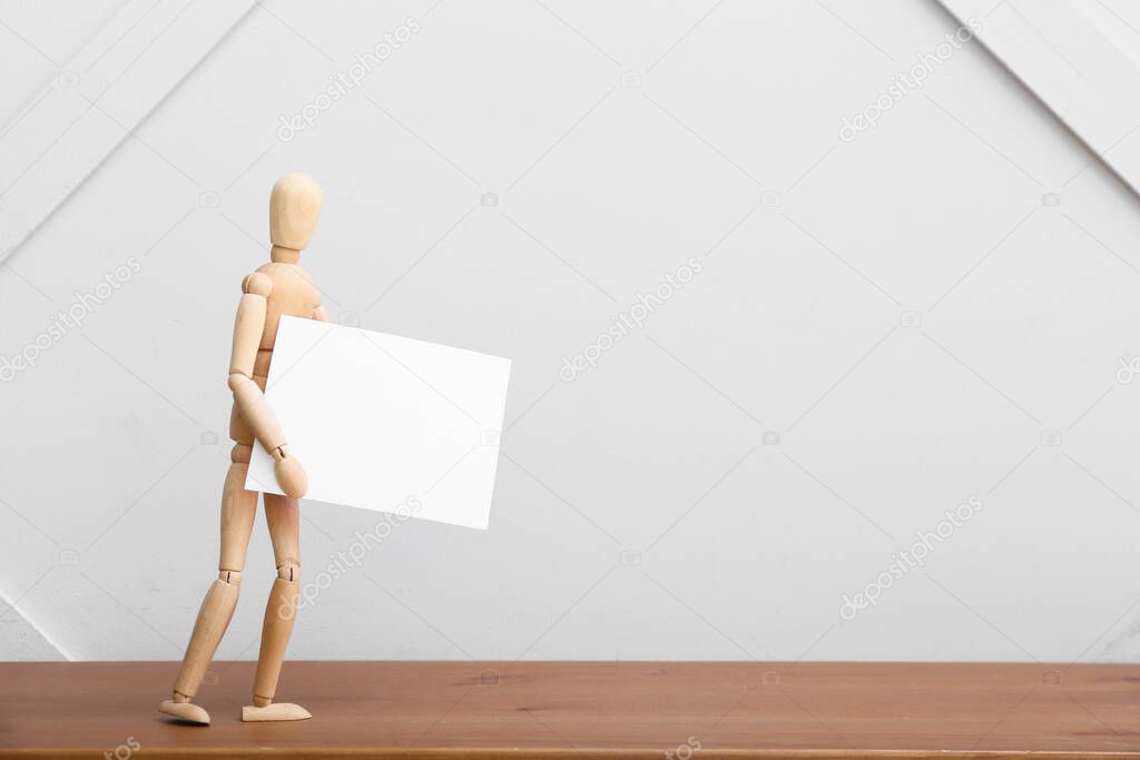 Wooden mannequin with blank poster on table