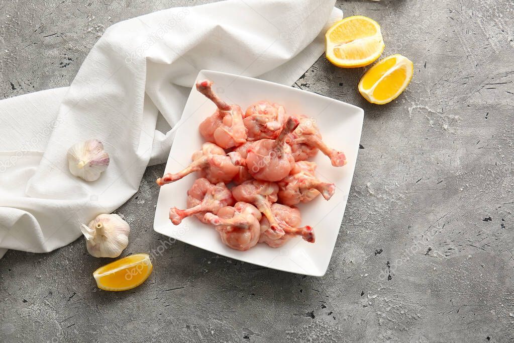 Plate with raw chicken lollipops on grey background