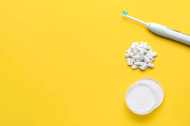 Çiklet, elektrikli diş fırçası ve arka planda diş pudrası.