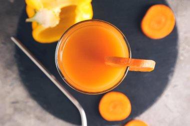 Gri arka planda havuç ve dolmalık biberli sağlıklı bir içecek. Yakın plan.