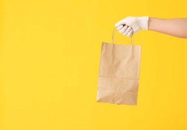 Renk arkaplanında kese kağıdı olan bir kurye eli