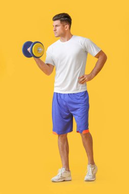 Renkli arka planda dambıl olan sportif genç adam eğitimi.