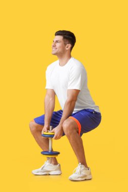 Renkli arka planda dambıl olan sportif genç adam eğitimi.