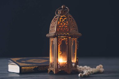 Müslüman lambası, tasbih ve Kuran koyu arkaplanda