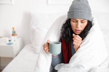 Evde sıcak çay içen hasta genç bir kadın.