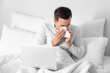 Evde çalışan laptoplu hasta bir adam.