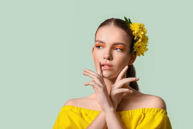 Yaratıcı makyajlı güzel bir genç kadının portresi ve renkli arka planda saçları olan çiçekler.