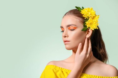 Yaratıcı makyajlı güzel bir genç kadının portresi ve renkli arka planda saçları olan çiçekler.