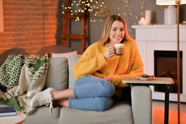 Güzel genç bayan evde sıcak çikolata içiyor.