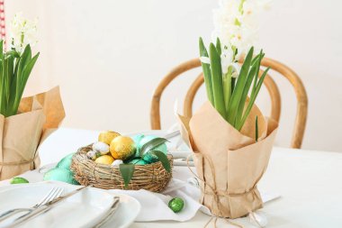 Çikolatalı yuva Paskalya yumurtaları ve çiçekler masada.