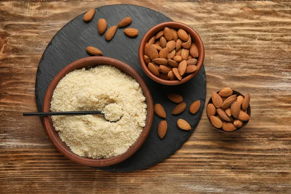 Bowl with almond flour on wooden background