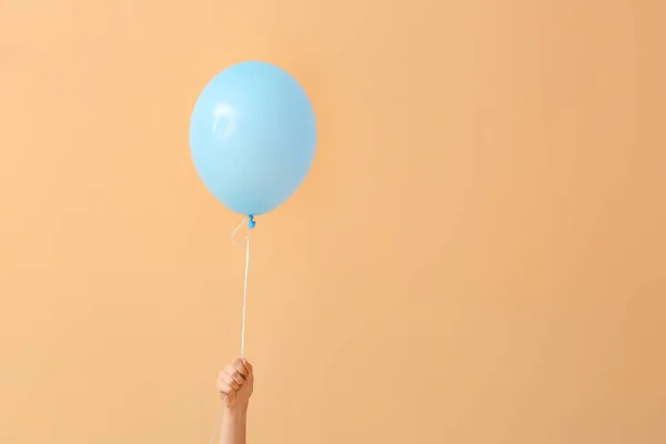 Human hand with air balloon on color background