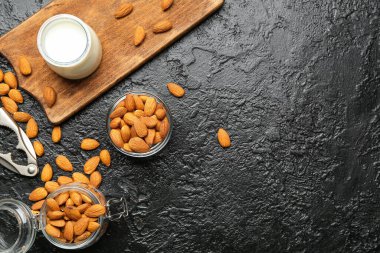 Sağlıklı badem kavanozu koyu arkaplanda süt ve fındık.