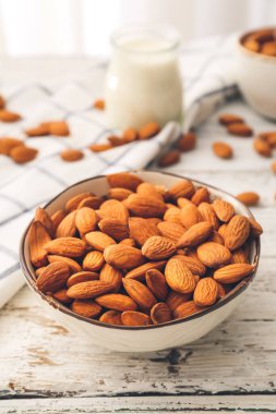 Hafif ahşap arka planda bir kase sağlıklı badem.