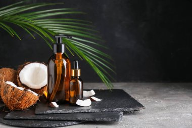 Koyu arkaplanda hindistan cevizi yağı şişeleri olan kompozisyon