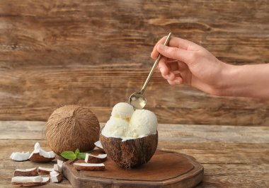 Ahşap arka planda lezzetli hindistan cevizli dondurmalı kadın eli.