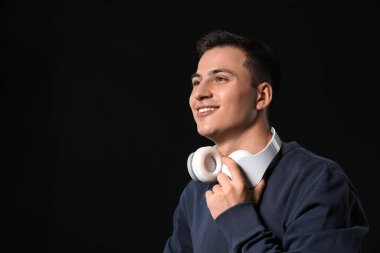 Siyah arka planda kulaklıkları olan yakışıklı bir genç.