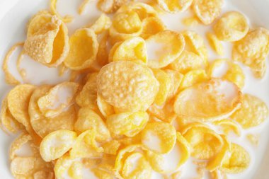 Arka planda süt bulunan lezzetli mısır gevrekleri, yakın plan.