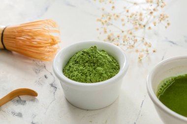 Pudralanmış kibrit çayı ve açık arkaplanda chasen ile kase