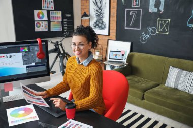 Genç bayan tasarımcı ofiste çalışıyor.