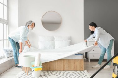 Olgun çift yatak odalarını temizliyor.