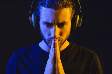 Yakışıklı genç adam karanlık arka planda müzik dinliyor.