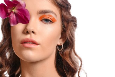 Yaratıcı makyajlı, beyaz arka planda orkide çiçeği olan güzel bir genç kadının portresi.