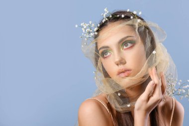 Yaratıcı makyajı ve renkli çiçekleri olan güzel bir genç kadının portresi.