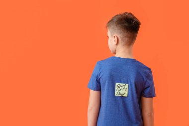 Renkli arka planda küçük çocuğun sırtında APRIL FOOLS GÜNÜ yazılı yapışkan not