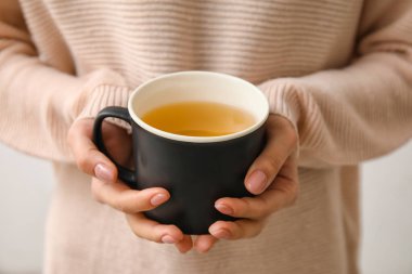 Bir fincan sıcak çay içen kadın, yakın plan.