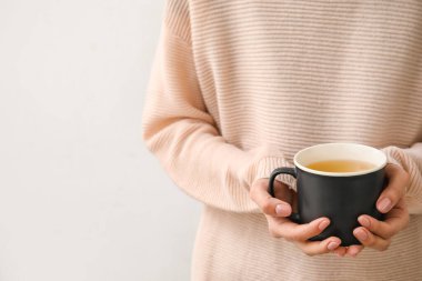 Hafif arka planda bir fincan sıcak çayı olan kadın.