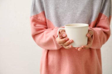 Hafif arka planda bir fincan sıcak çayı olan kadın.