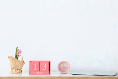 13 Mayıs tarihli küp takvimi, alarmlı saat ve çiçekler odada.
