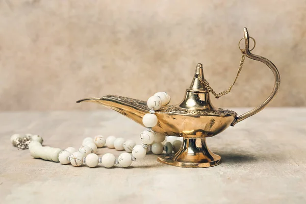 Aladdin lamp of wishes and tasbih on grey background