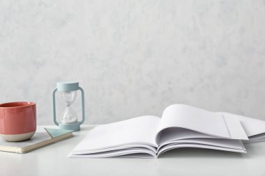 Boş dergileri aç, bir fincan kahve ve masada kum saati.